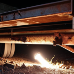 **

A close-up shot of a rusty trailer frame underneath a trailer. Focus on the corroded metal, with a flashlight beam illuminating the damage. The composition should evoke a sense of hidden problems beneath a seemingly normal exterior.

**